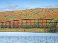 Fall Foliage colorfully silhouettes bridge across Snow Shed pond at Killington.