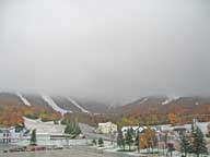 =Killington peak covered in clouds with snow on lower elevations.